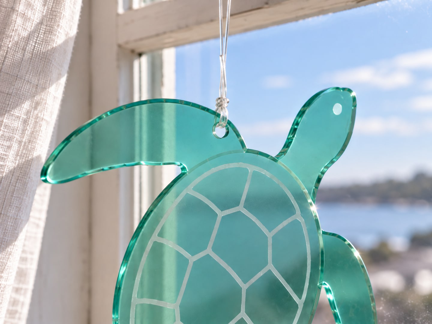 Close view of the same acrylic turtle showing the cord tied through its hole, thin edges and frosted shell pattern
